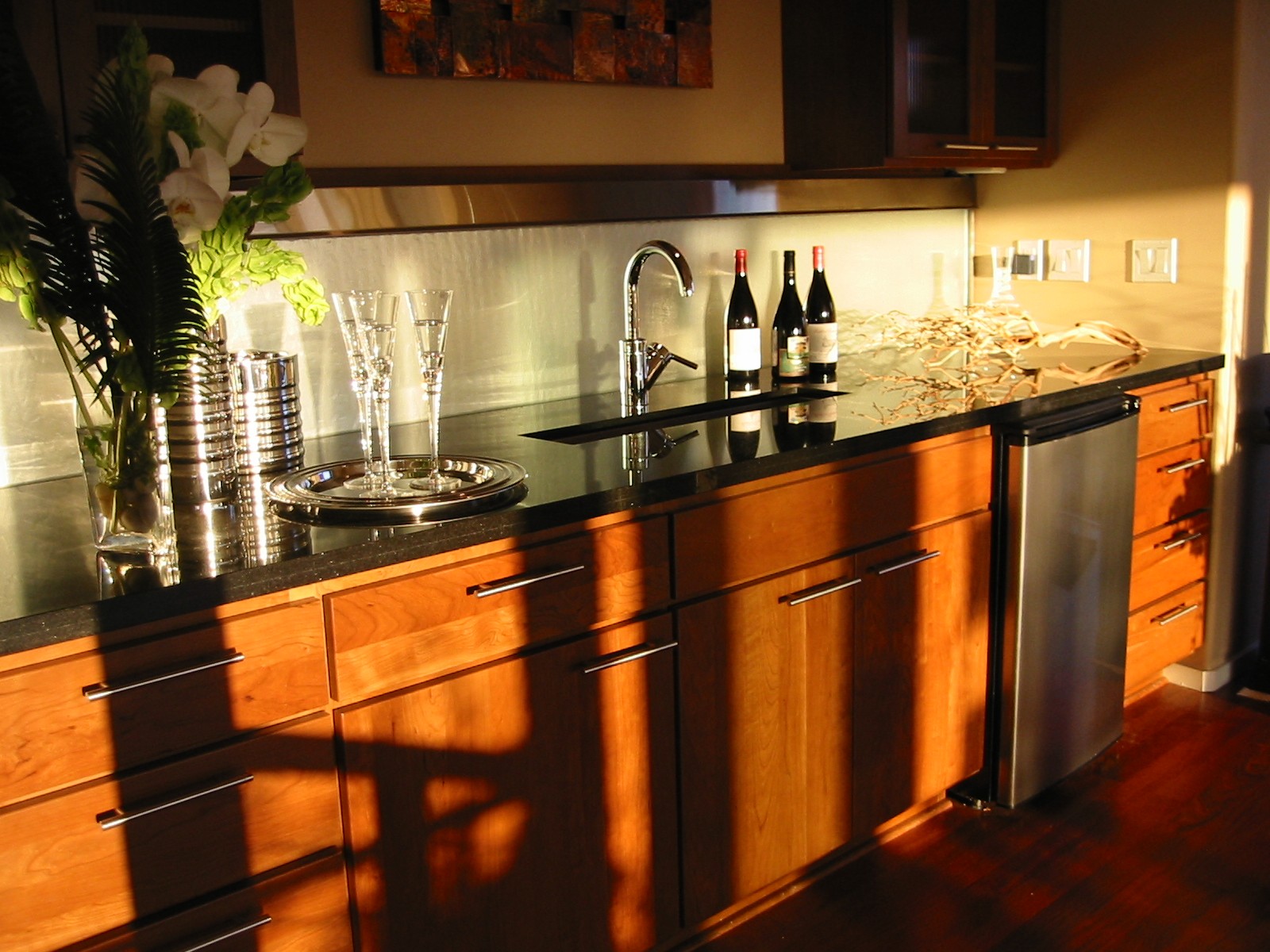 West Seattle, WA. residence. 10 ft x 18in tall frosted glass wall at back of bar, integrated into granite counter, lighting within valance new construction remote pump.