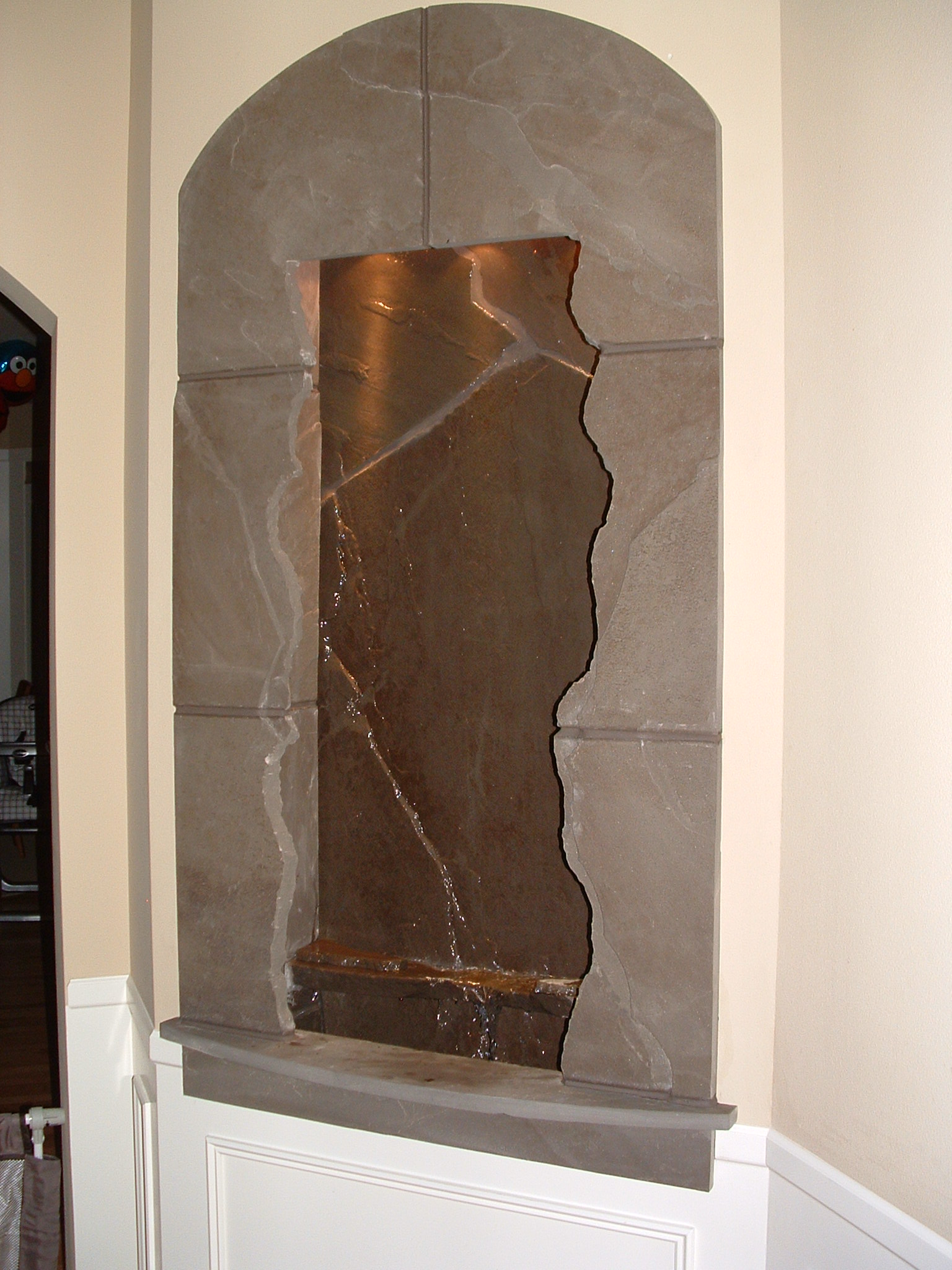 Factoria, WA. residence 40 in x 6 ft. This piece is made out of blue stone, making use of an existing art nook alcove, lighting in valance, deep basin for extra sound as water pours off the built in spillway, existing home. 